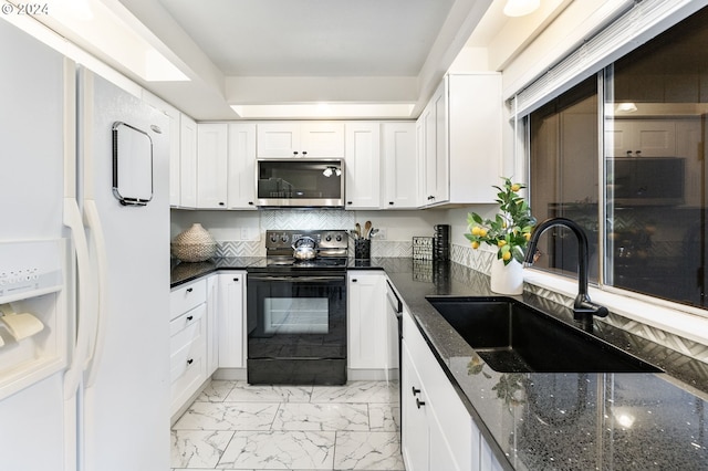 kitchen with dark stone counters, white cabinetry, sink, and stainless steel appliances