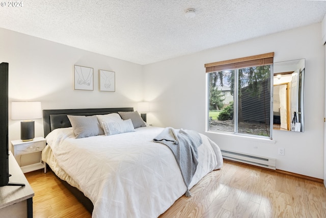 bedroom with a textured ceiling, light hardwood / wood-style floors, and a baseboard heating unit