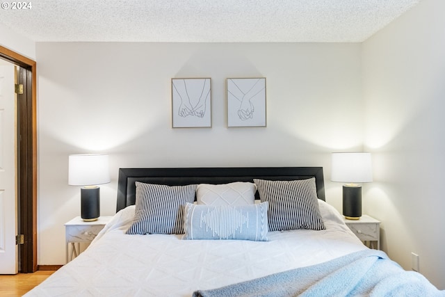 bedroom featuring a textured ceiling and light hardwood / wood-style flooring