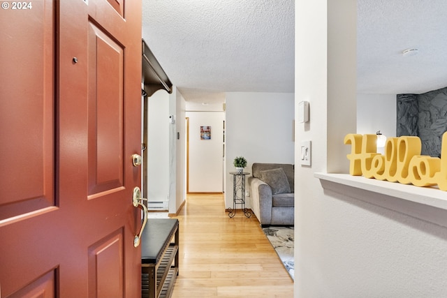 entrance foyer with a baseboard radiator, light hardwood / wood-style floors, and a textured ceiling