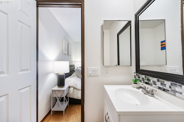 bathroom featuring hardwood / wood-style flooring, decorative backsplash, and vanity