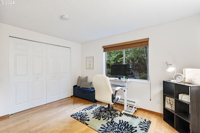 office space with a textured ceiling, wood-type flooring, and baseboard heating