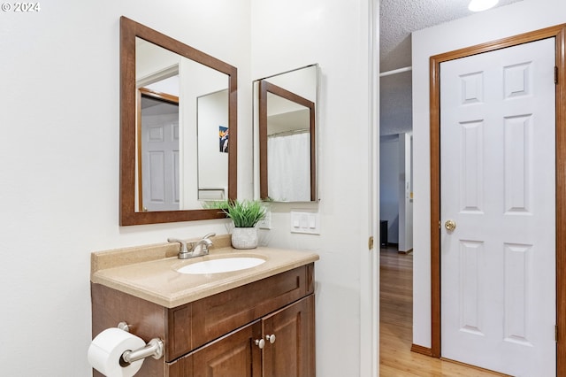 bathroom featuring wood-type flooring, vanity, and a textured ceiling