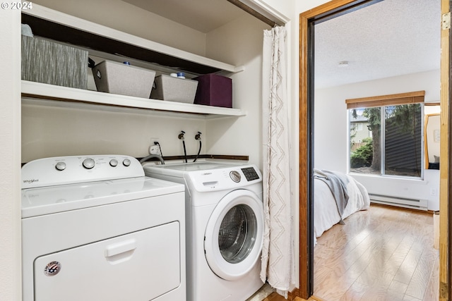 washroom featuring separate washer and dryer, a textured ceiling, light hardwood / wood-style floors, and a baseboard heating unit