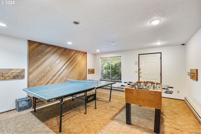 game room featuring light colored carpet, a textured ceiling, and a baseboard heating unit