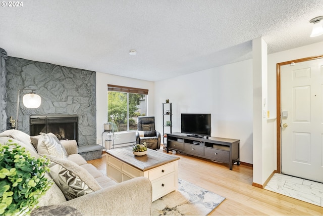 living room with a textured ceiling, a fireplace, and light hardwood / wood-style flooring