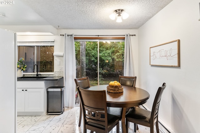 dining area featuring a textured ceiling, sink, and a baseboard heating unit