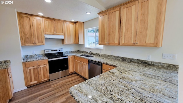 kitchen with sink, appliances with stainless steel finishes, light stone counters, light hardwood / wood-style floors, and a textured ceiling