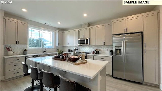 kitchen with decorative backsplash, light hardwood / wood-style floors, appliances with stainless steel finishes, and sink