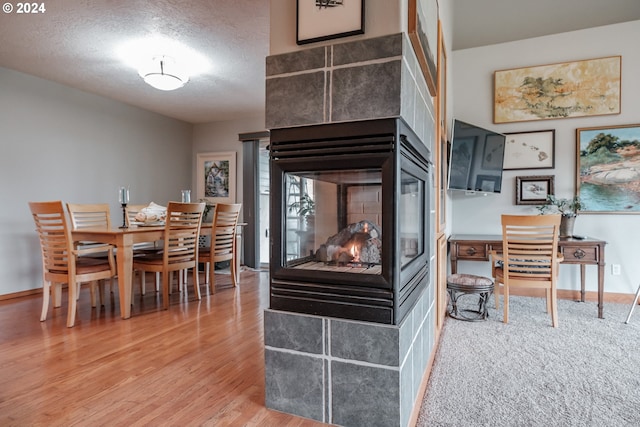 kitchen featuring a multi sided fireplace, a textured ceiling, and wood-type flooring