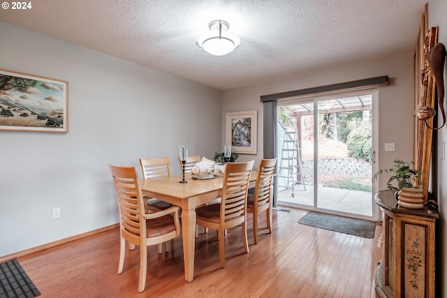 dining space with light wood-type flooring and a textured ceiling