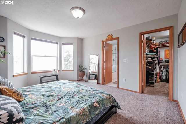 carpeted bedroom featuring a closet, connected bathroom, a textured ceiling, and a spacious closet