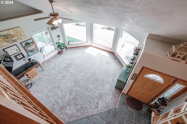 carpeted living room with a textured ceiling, ceiling fan, and vaulted ceiling