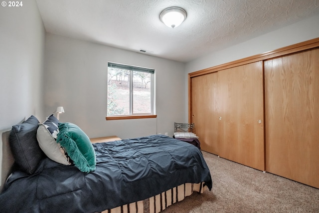 carpeted bedroom with a textured ceiling and a closet