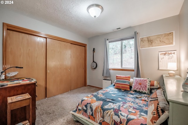 carpeted bedroom featuring a textured ceiling and a closet