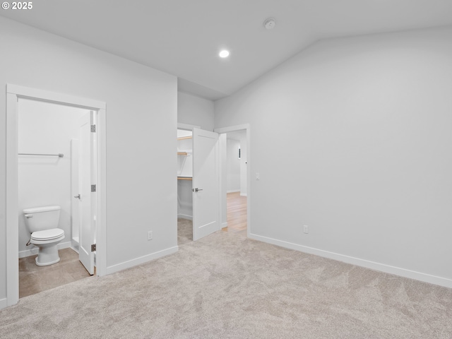 unfurnished bedroom with carpet floors, a spacious closet, connected bathroom, and baseboards