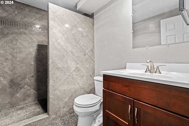 bathroom featuring tiled shower, toilet, and vanity