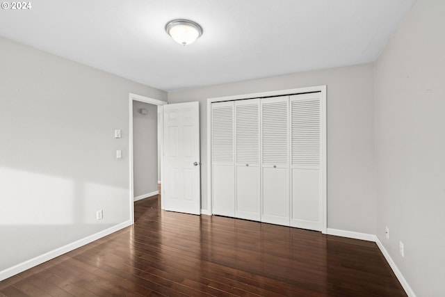 unfurnished bedroom with dark wood-type flooring and a closet