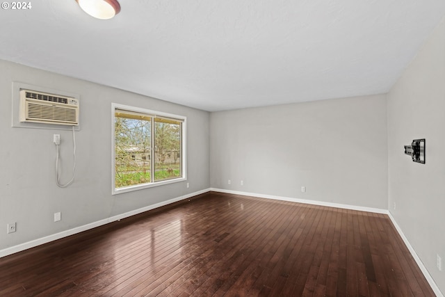 unfurnished room featuring a wall mounted AC and dark hardwood / wood-style floors