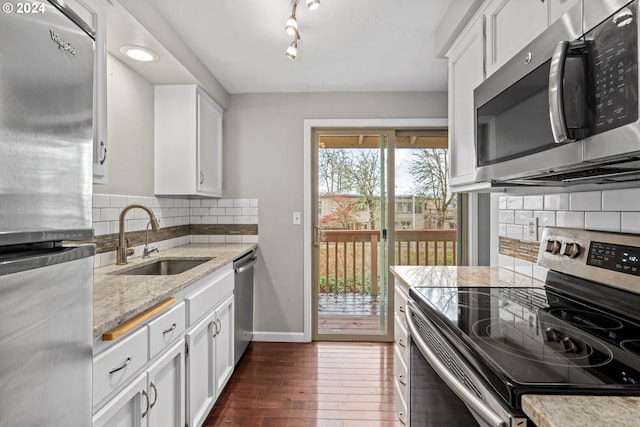 kitchen with sink, stainless steel appliances, white cabinetry, and light stone countertops