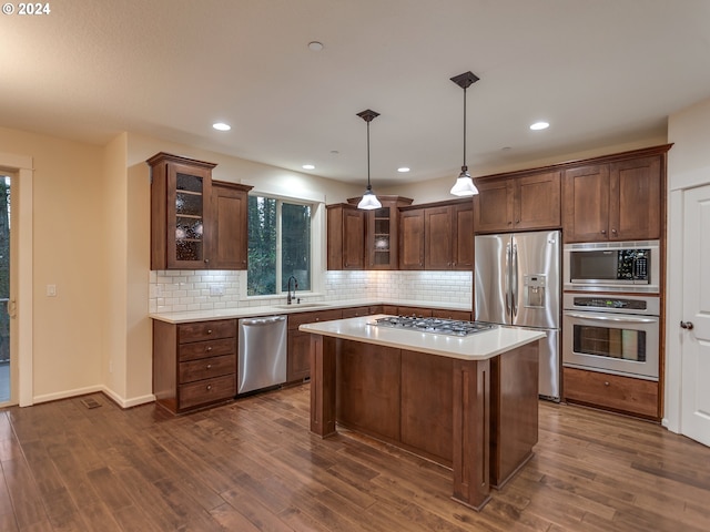 kitchen with sink, dark hardwood / wood-style floors, pendant lighting, a kitchen island, and appliances with stainless steel finishes