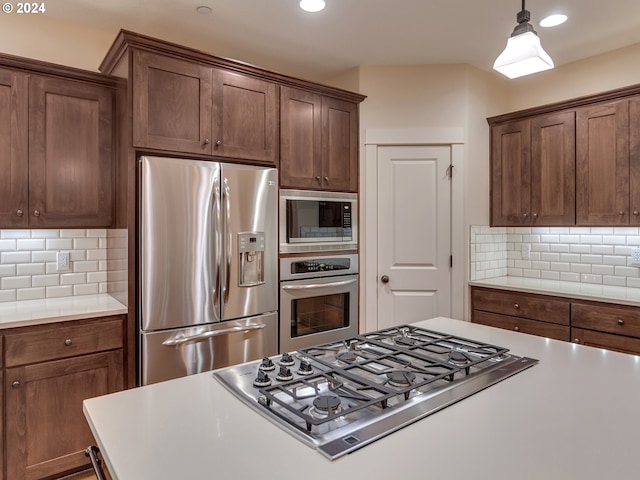 kitchen with decorative backsplash, appliances with stainless steel finishes, dark brown cabinetry, and decorative light fixtures