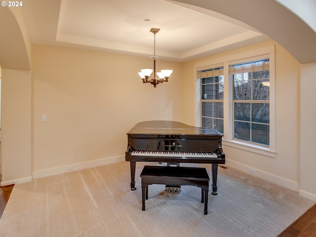 misc room featuring a raised ceiling, carpet floors, and a chandelier