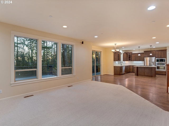 unfurnished living room with a chandelier, dark hardwood / wood-style floors, and sink