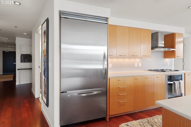 kitchen featuring backsplash, wall chimney range hood, stainless steel appliances, and dark wood-type flooring