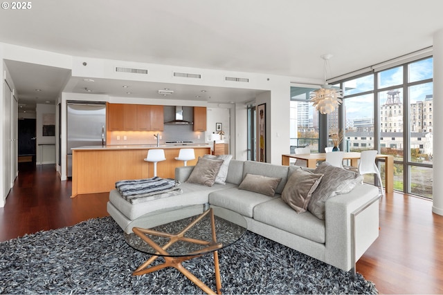 living room featuring a healthy amount of sunlight, an inviting chandelier, wood-type flooring, and a wall of windows