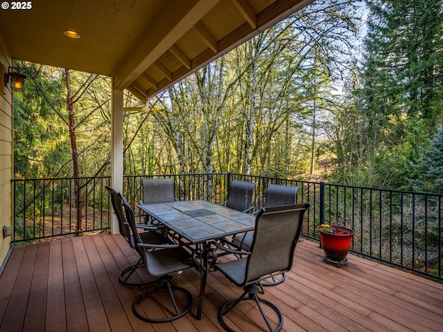 deck with a forest view and outdoor dining space