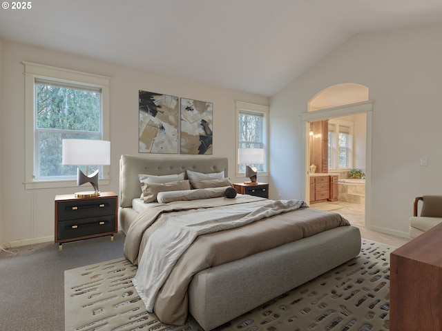 carpeted bedroom with lofted ceiling, baseboards, and ensuite bathroom