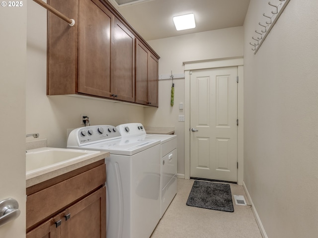 clothes washing area with washing machine and dryer, baseboards, cabinet space, and a sink