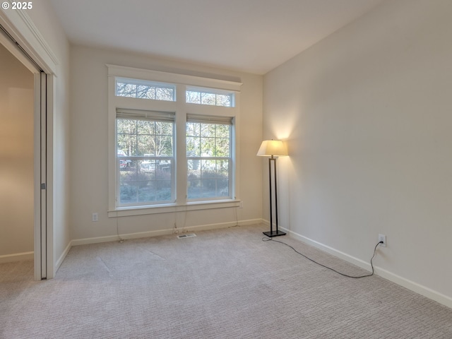 carpeted spare room with visible vents and baseboards