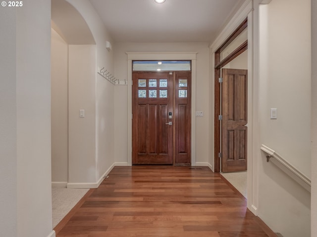 entryway with arched walkways, baseboards, light wood finished floors, and recessed lighting