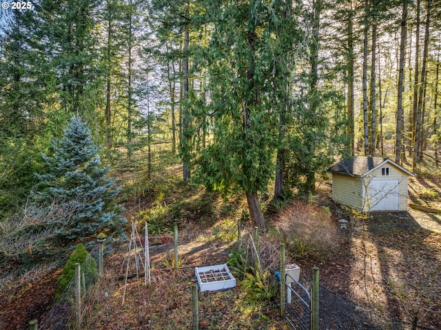 view of yard featuring a forest view, a storage shed, and an outdoor structure