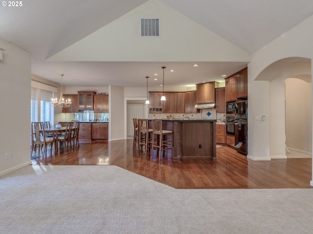 kitchen with arched walkways, carpet floors, visible vents, and custom range hood