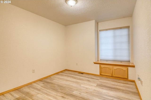 unfurnished room featuring a textured ceiling and light wood-type flooring