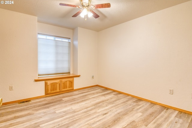 unfurnished room with ceiling fan, light wood-type flooring, and a textured ceiling