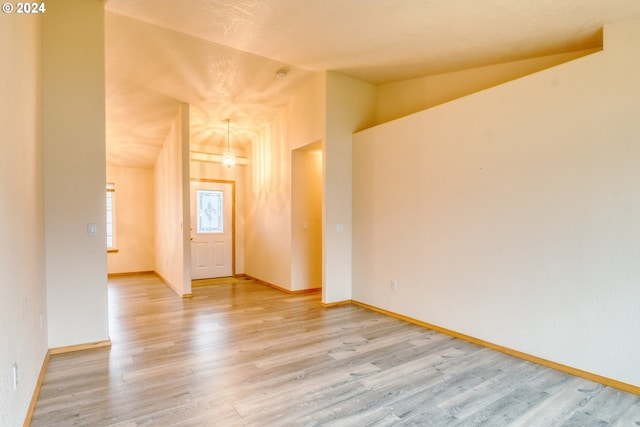 unfurnished room featuring light hardwood / wood-style flooring and vaulted ceiling