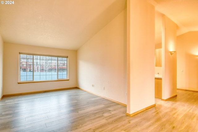 spare room with hardwood / wood-style floors and lofted ceiling