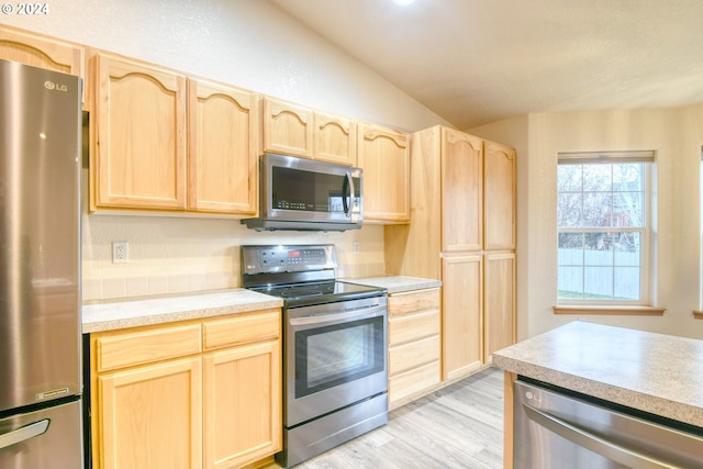 kitchen featuring light brown cabinets, lofted ceiling, appliances with stainless steel finishes, and light hardwood / wood-style flooring