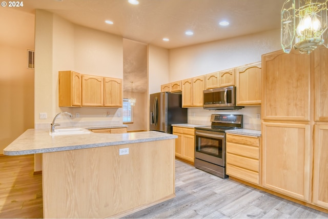 kitchen featuring light brown cabinets, stainless steel appliances, light hardwood / wood-style flooring, kitchen peninsula, and a towering ceiling