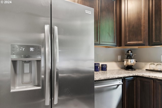 kitchen featuring light stone counters, dark brown cabinetry, and stainless steel refrigerator with ice dispenser