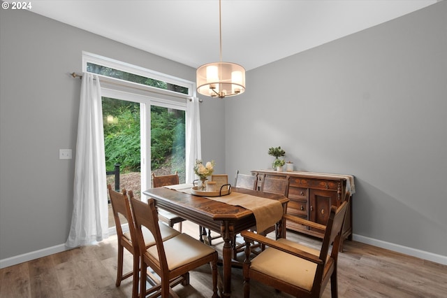 dining area with light wood-style flooring, baseboards, and a chandelier