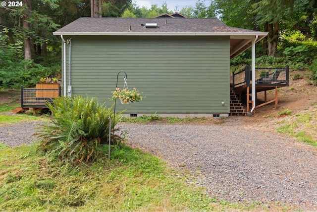 view of side of home with driveway, a shingled roof, crawl space, stairs, and a deck