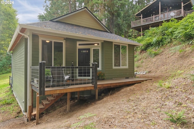 back of house featuring covered porch and a shingled roof