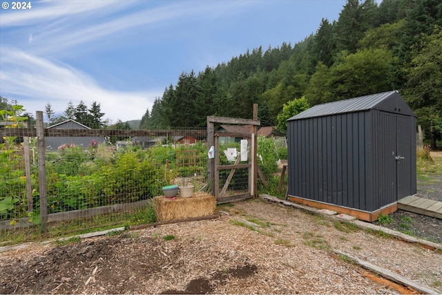 exterior space featuring a garden, fence, a storage unit, and an outbuilding