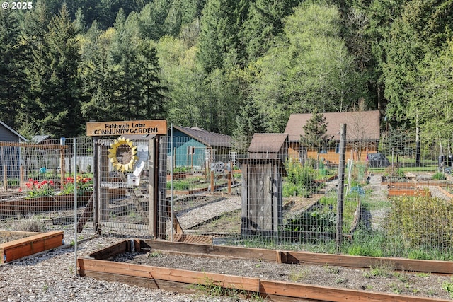 gate featuring a vegetable garden, fence, and a wooded view