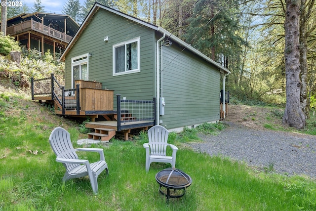 rear view of property with a fire pit, a deck, and crawl space